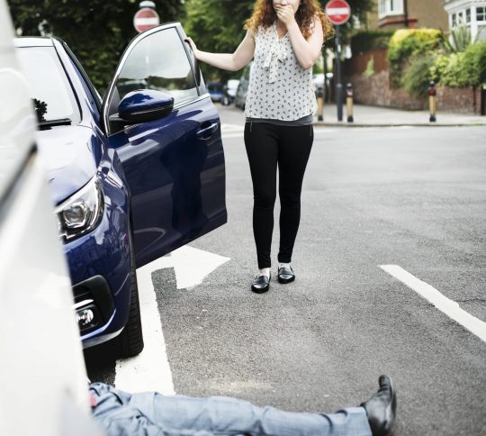 Person lying on the ground after a car accident